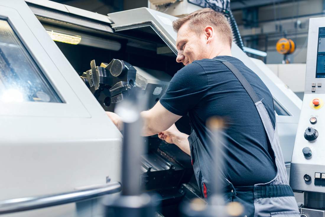Machinist setting up a CNC lathe on a factory floor
