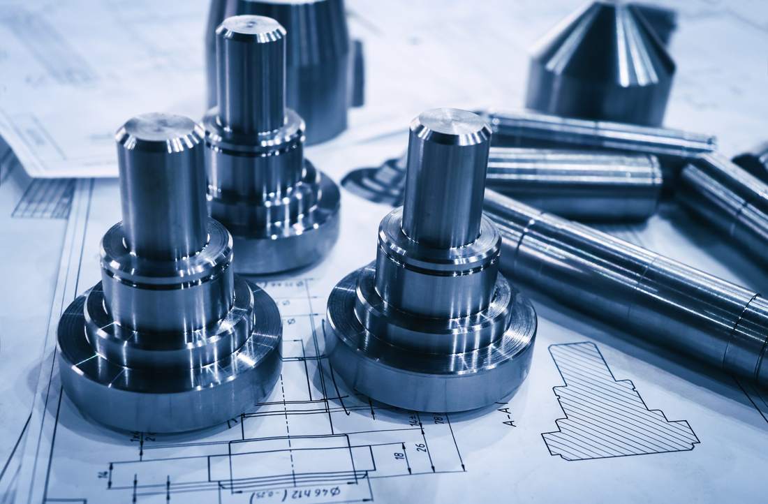 Machined steel parts laid out on engineering blueprints